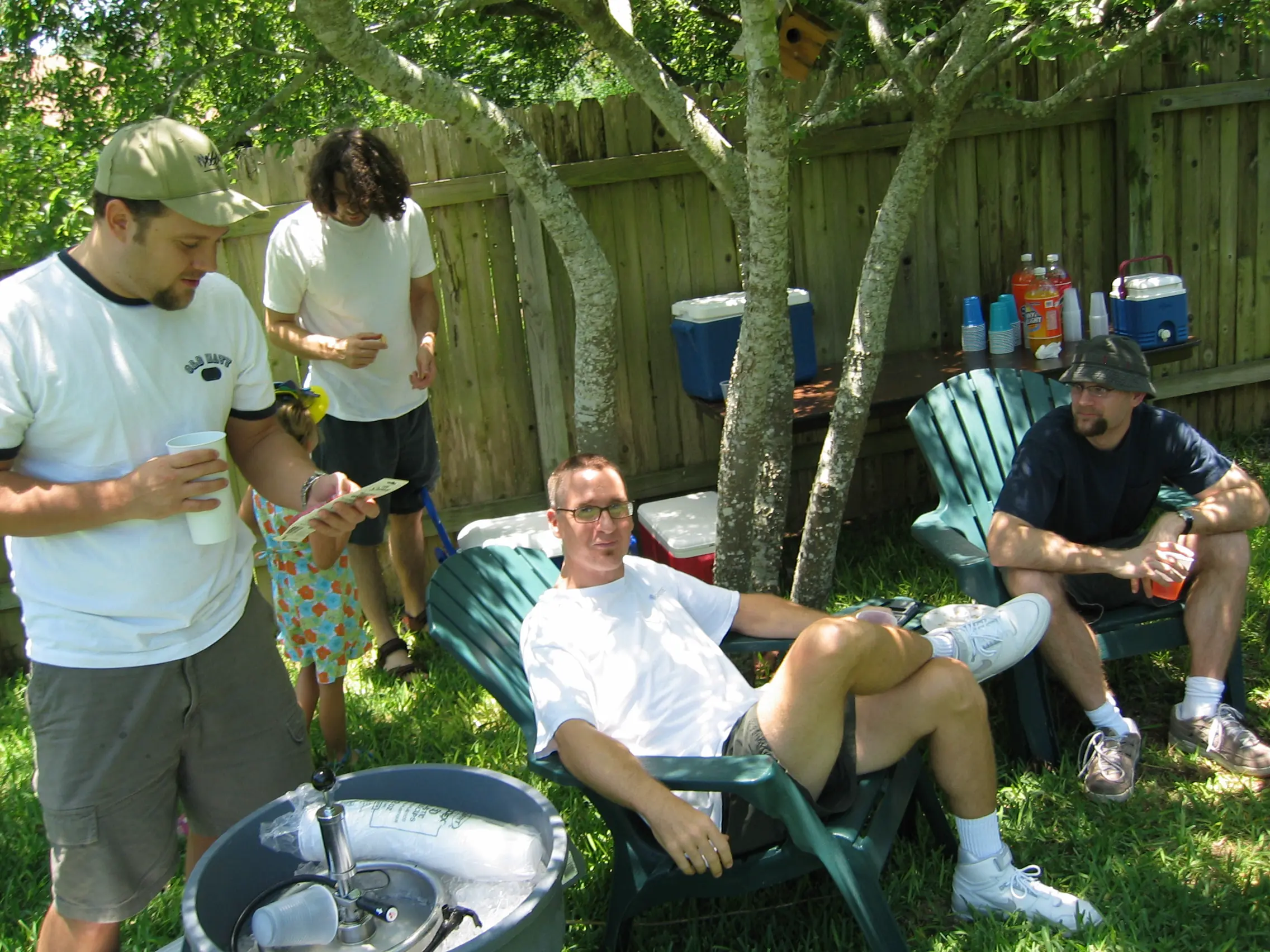 Joe relaxing in a green Adirondack chair at his backyard birthday party, with friends and a keg nearby
