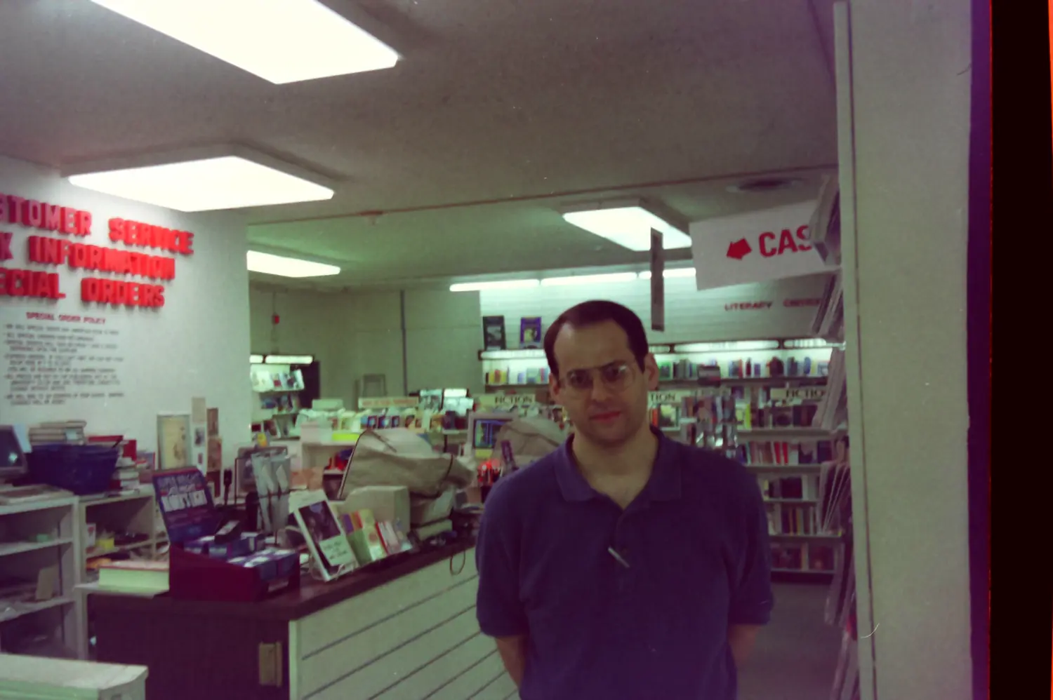 A coworker standing in front of the Customer Service and Special Orders desk in the University Co-op General Books department, 1993
